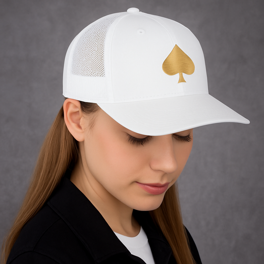 Frau mit weißer Trucker-Cap, goldenes Pik-Symbol auf der Vorderseite, Kopf leicht gesenkt.