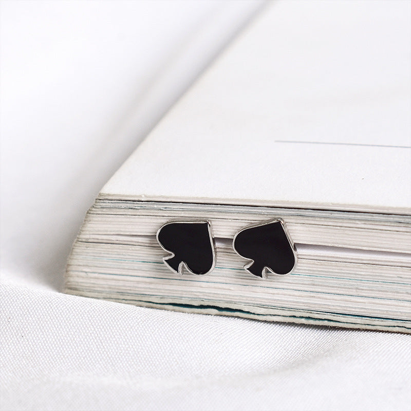 PIK Symbol Ohrstecker Schwarz Buch im Hintergrund